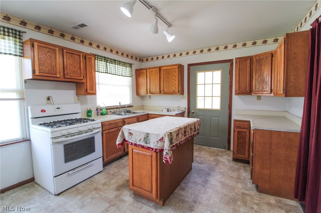 39353 Walnut Camp Road Sardis, OH 43946 - Photo 10 of 42 Kitchen featuring light tile floors, track lighting, gas range gas stove, sink, and a center island