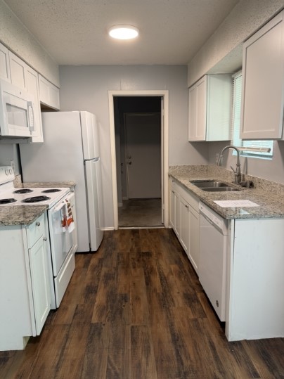 112 Cockerham Street, Unit A Kyle, TX 78640 - Photo 1 of 1 Kitchen featuring white appliances, white cabinetry, dark wood-style flooring, and light granite counters
