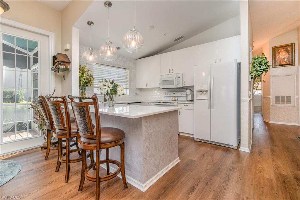 367 Dover Place, Unit 1006 Naples, FL 34104 - Photo 15 of 31 a kitchen with stainless steel appliances granite countertop a stove a refrigerator a kitchen island a dining table and chairs with wooden floor