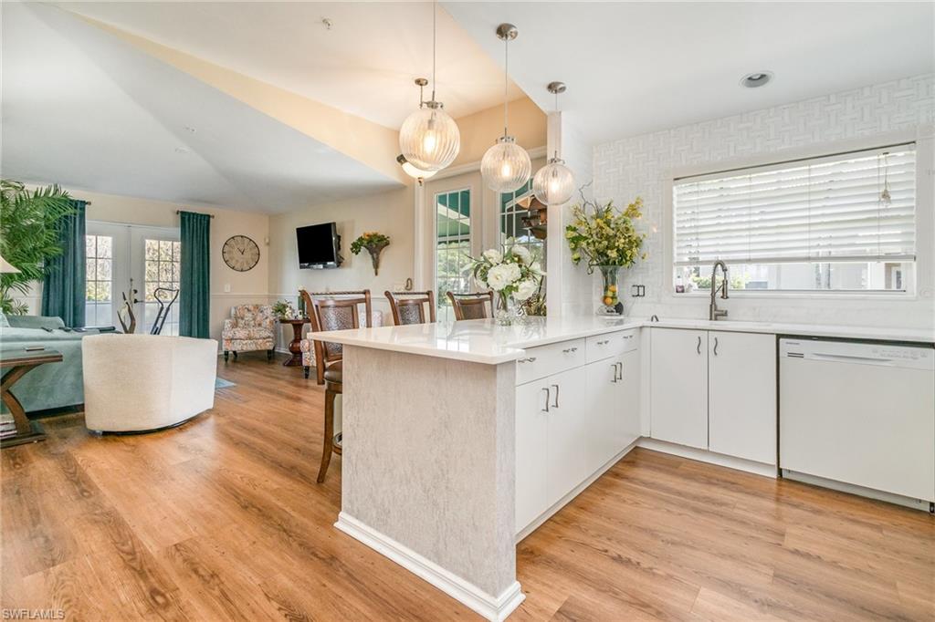 367 Dover Place, Unit 1006 Naples, FL 34104 - Photo 7 of 31 a large white kitchen with a large island oven a sink dishwasher and white cabinets with wooden floor