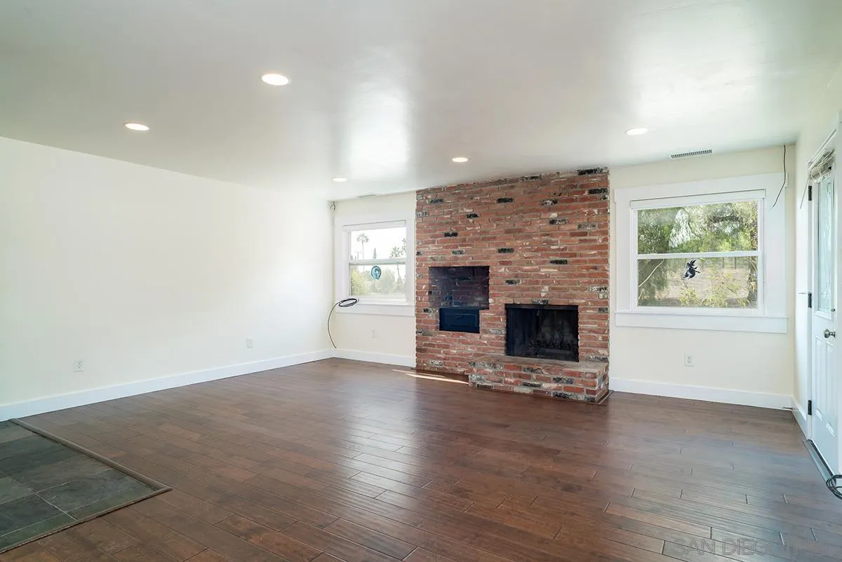 6777 West Lilac Road Bonsall, CA 92003 - Photo 15 of 36 an empty room with fireplace and wooden floor