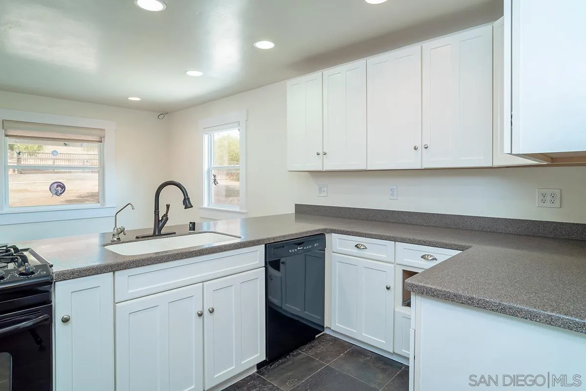 6777 West Lilac Road Bonsall, CA 92003 - Photo 21 of 36 a kitchen with white cabinets and a sink