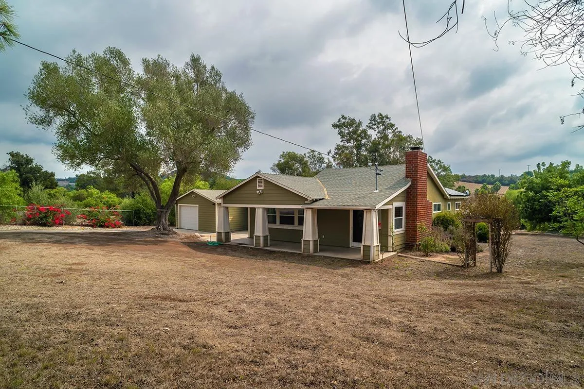 6777 West Lilac Road Bonsall, CA 92003 - Photo 9 of 36 a front view of a house with a yard and trees