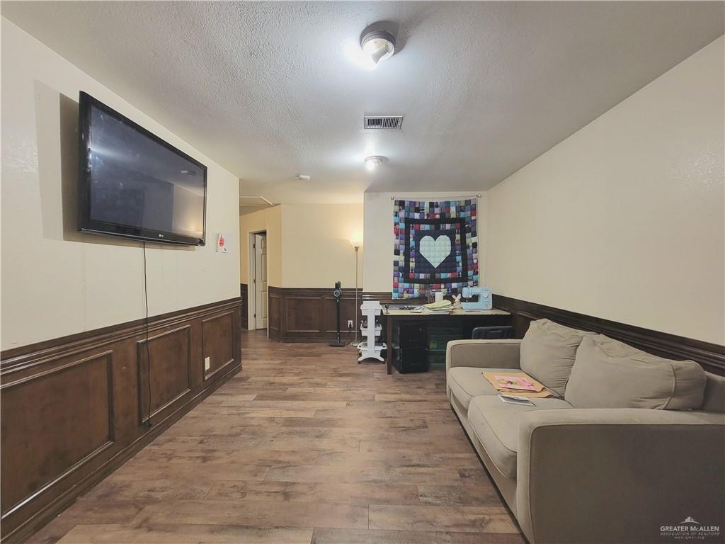 206 South Arroyo Boulevard Rio Hondo, TX 78583 - Photo 19 of 42 Living room with a textured ceiling, dark wood finished floors, a wainscoted wall, and a decorative wall