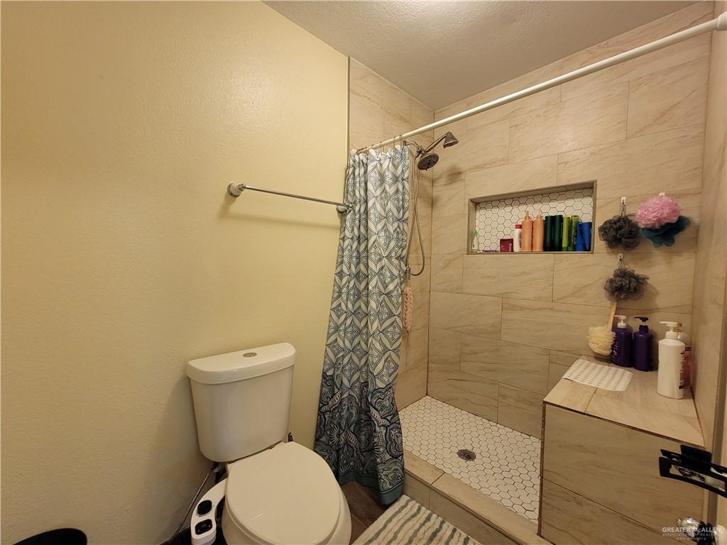 206 South Arroyo Boulevard Rio Hondo, TX 78583 - Photo 22 of 42 1st Bathroom featuring a tile shower and a textured ceiling