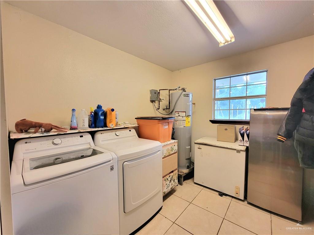 206 South Arroyo Boulevard Rio Hondo, TX 78583 - Photo 34 of 42 Laundry room featuring washing machine and clothes dryer, light tile patterned floors, and electric water heater