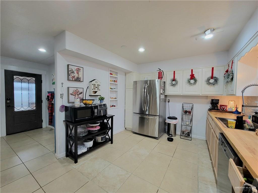 206 South Arroyo Boulevard Rio Hondo, TX 78583 - Photo 6 of 42 Kitchen featuring freestanding refrigerator, white cabinetry, light tile patterned flooring, black microwave, and recessed lighting