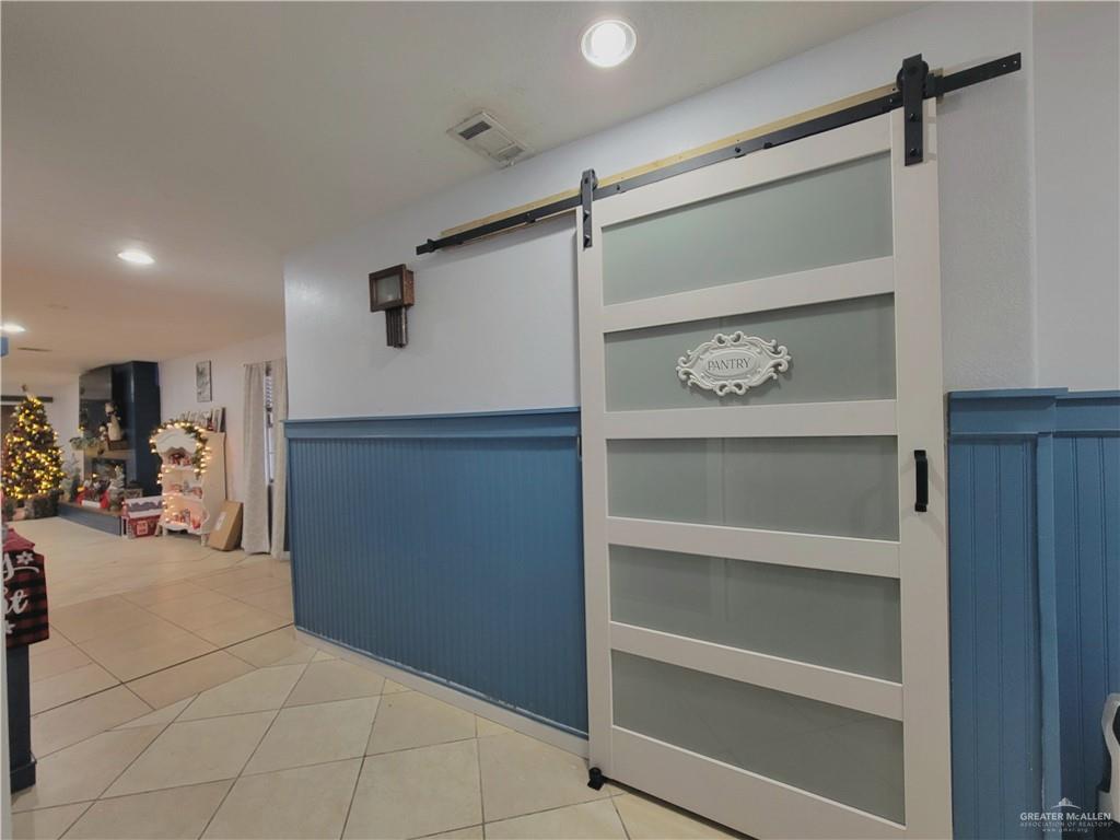 206 South Arroyo Boulevard Rio Hondo, TX 78583 - Photo 7 of 42 Hallway featuring a wainscoted wall, recessed lighting, a barn door, and light tile patterned floors