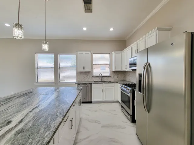 a kitchen with granite countertop stainless steel appliances a refrigerator oven a sink and a counter space