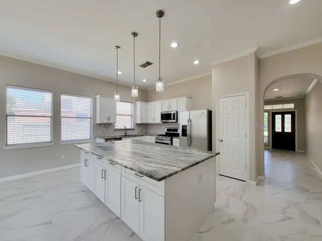 a kitchen with stainless steel appliances granite countertop a sink a oven a counter space and a refrigerator