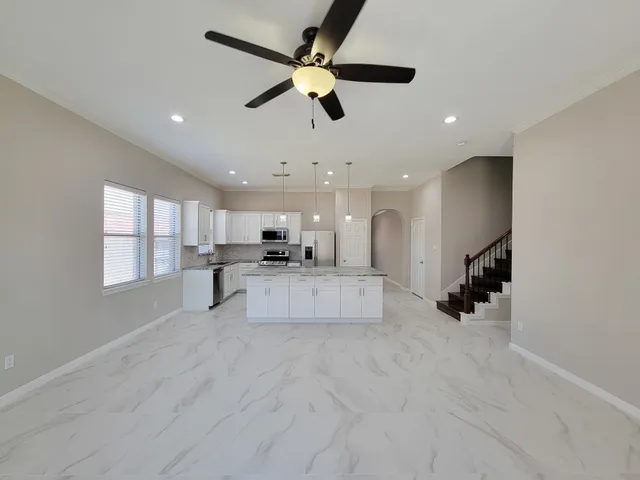 a living room with stainless steel appliances kitchen island furniture and a ceiling fan