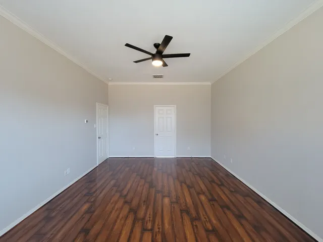 an empty room with wooden floor a ceiling fan and windows
