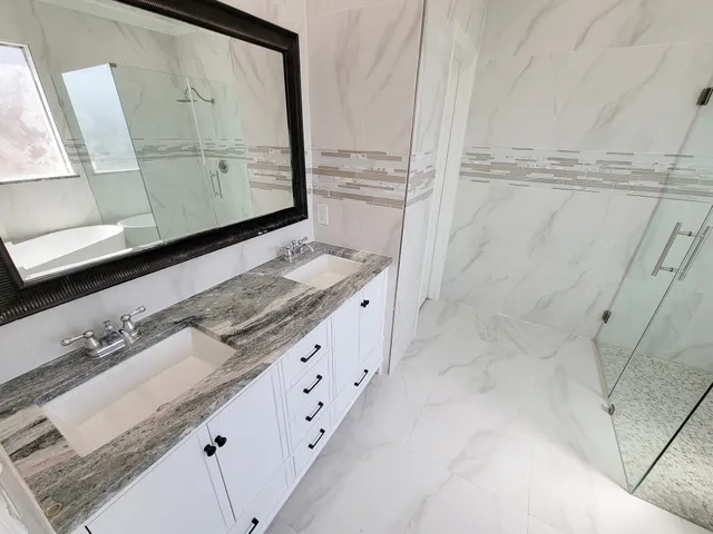 a bathroom with a granite countertop sink a mirror and shower