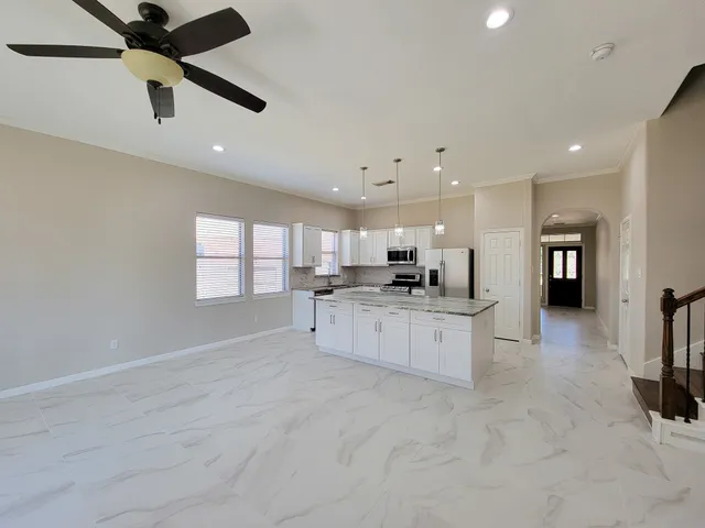 a large white kitchen with kitchen island a stove a sink dishwasher and a fireplace