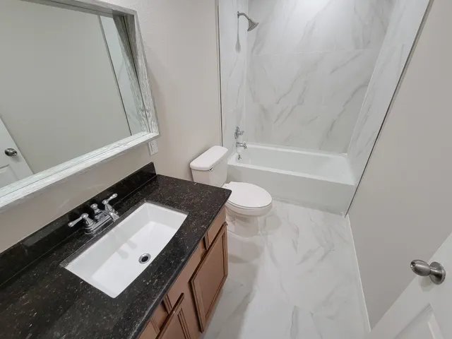 a bathroom with a sink a toilet a mirror and shower