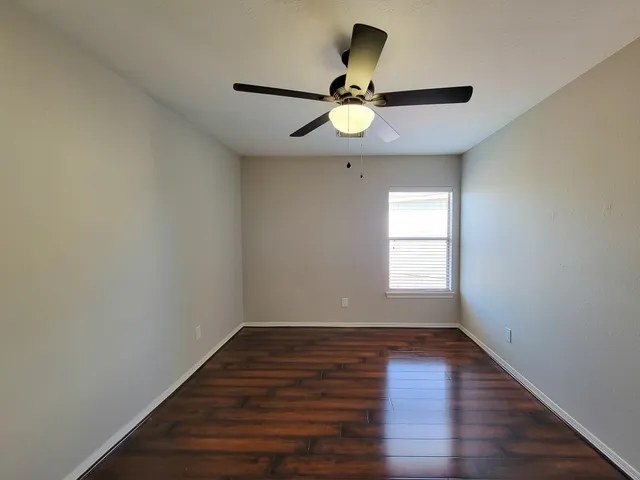 a view of a room with wooden floor and ceiling fan