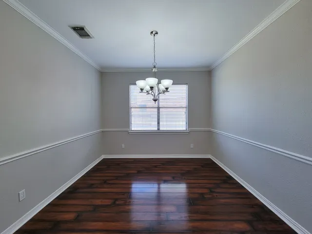 a view of a room with wooden floor chandelier and window