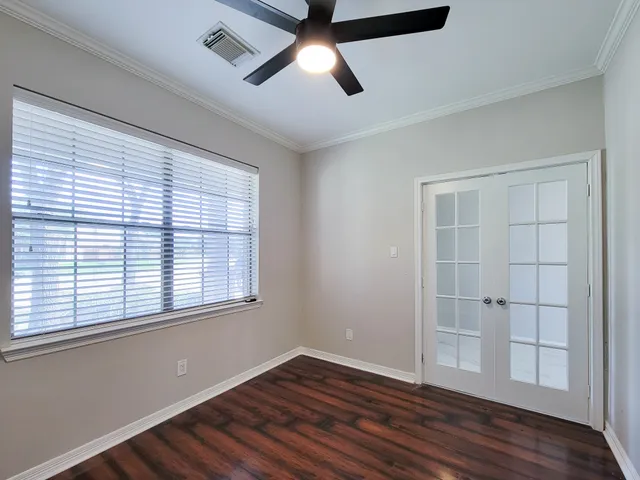 an empty room with wooden floor and windows