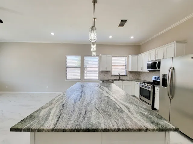 a large kitchen with granite countertop a stove a sink dishwasher a refrigerator and wooden floor