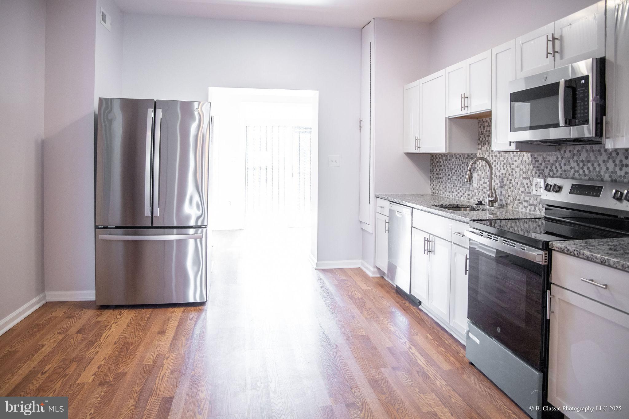3035 West Belvedere Avenue Baltimore, MD 21215 - Photo 16 of 49 a kitchen with stainless steel appliances granite countertop a refrigerator microwave and stove top oven