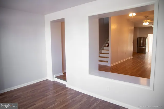 a view of a hallway with wooden floor and a bathroom