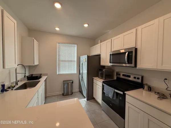 a kitchen with stainless steel appliances a stove a sink a refrigerator a microwave a refrigerator and cabinets