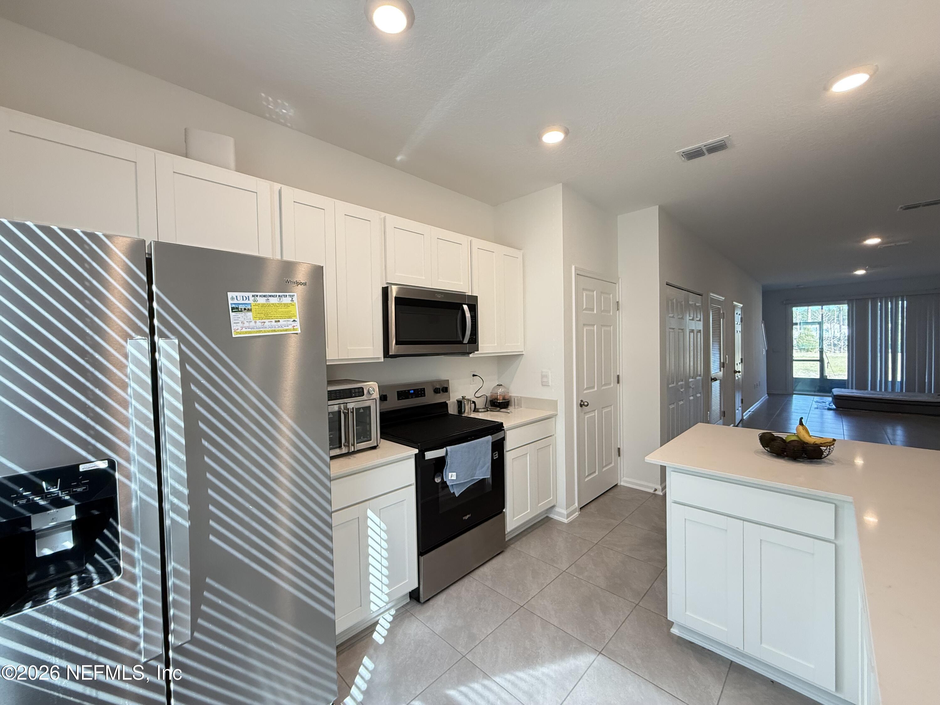 88 Crisanto Road St. Augustine, FL 32084 - Photo 3 of 21 a kitchen with stainless steel appliances kitchen island granite countertop a sink and stove top oven with wooden floor