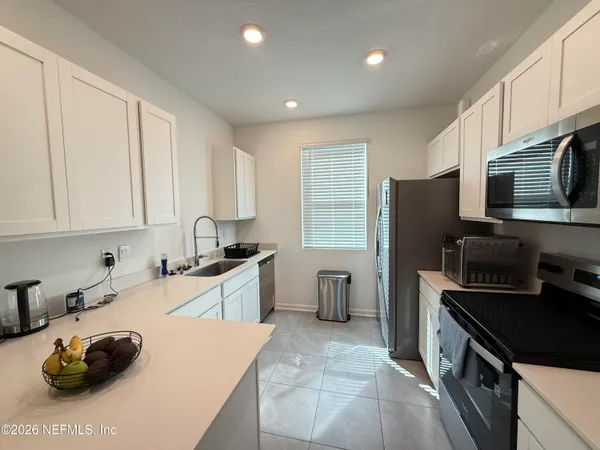 a kitchen with a sink a stove a refrigerator cabinets and a window