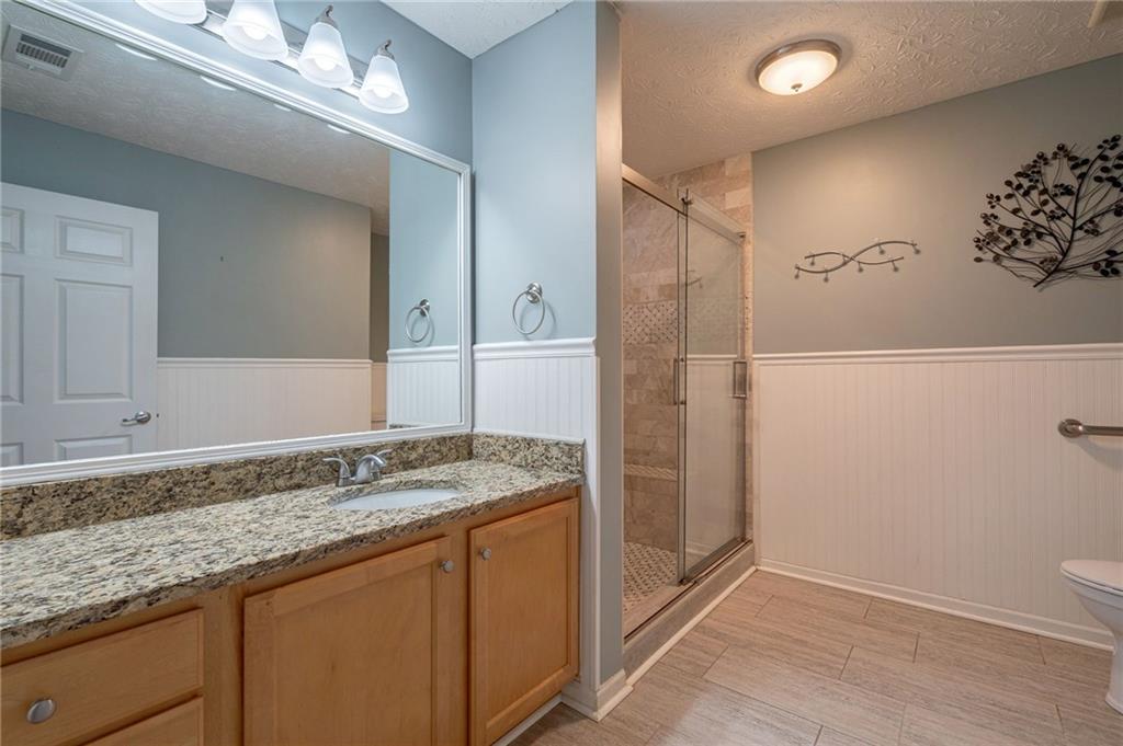 245 Memory Lane Winder, GA 30680 - Photo 27 of 62 a bathroom with a granite countertop sink a toilet and shower