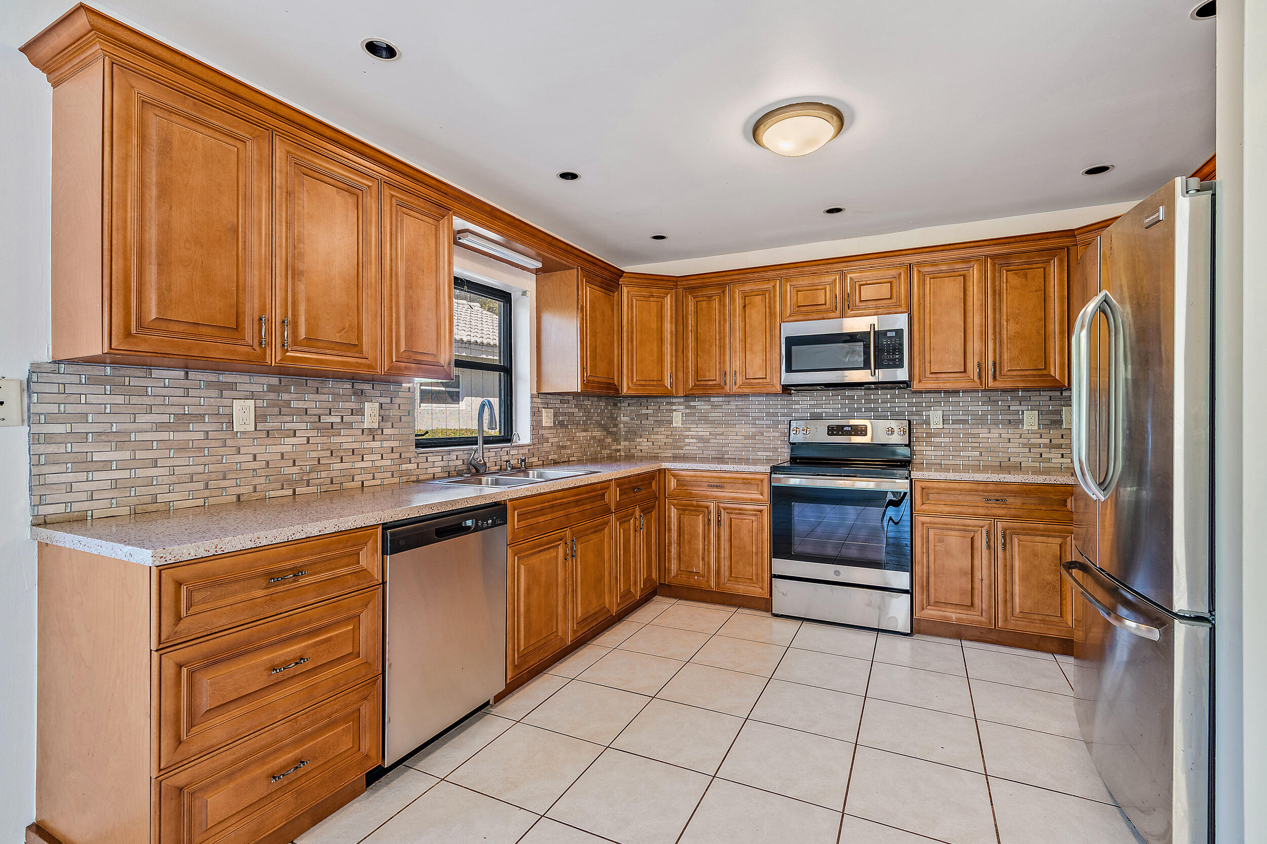 7938 Cloverfield Circle Boca Raton, FL 33433 - Photo 9 of 27 a kitchen with stainless steel appliances granite countertop a stove top oven a sink dishwasher and a refrigerator