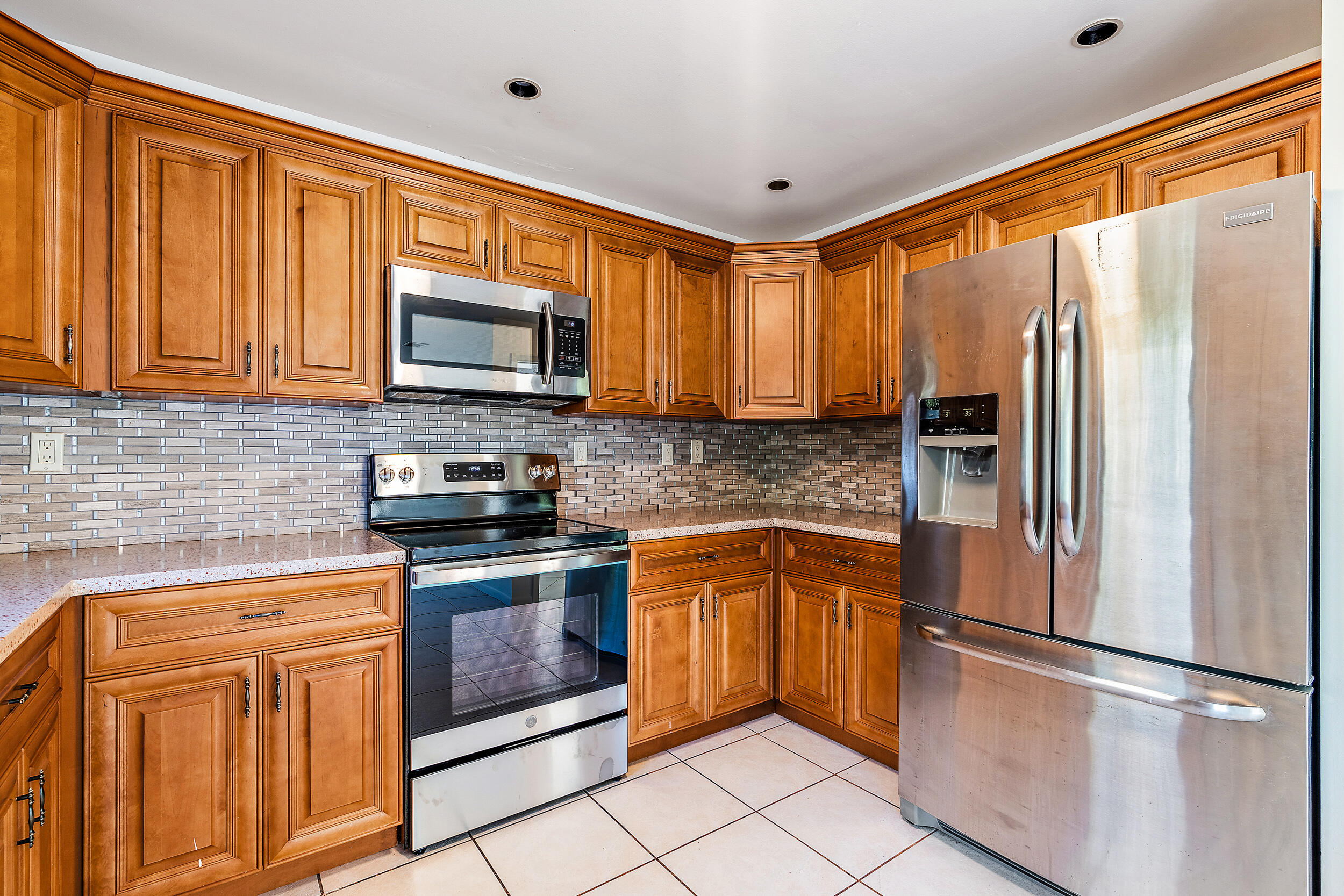 7938 Cloverfield Circle Boca Raton, FL 33433 - Photo 10 of 27 a kitchen with stainless steel appliances granite countertop a refrigerator stove top oven