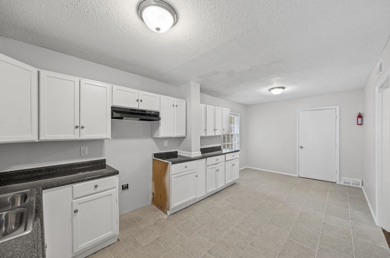 3843 Blue Jay Road Memphis, TN 38116 - Photo 11 of 23 Kitchen featuring dark countertops, white cabinets, and a textured ceiling