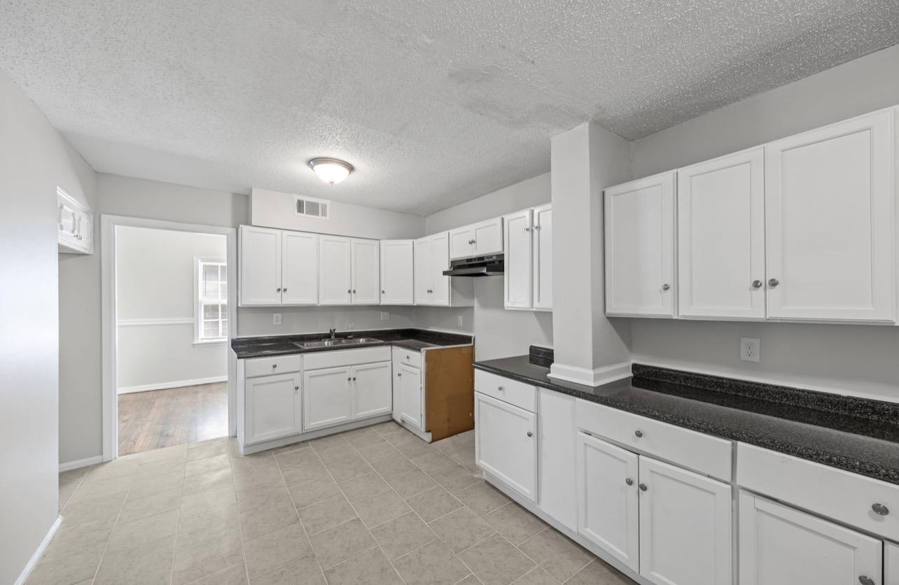 3843 Blue Jay Road Memphis, TN 38116 - Photo 12 of 23 Kitchen featuring dark countertops, white cabinetry, and a textured ceiling