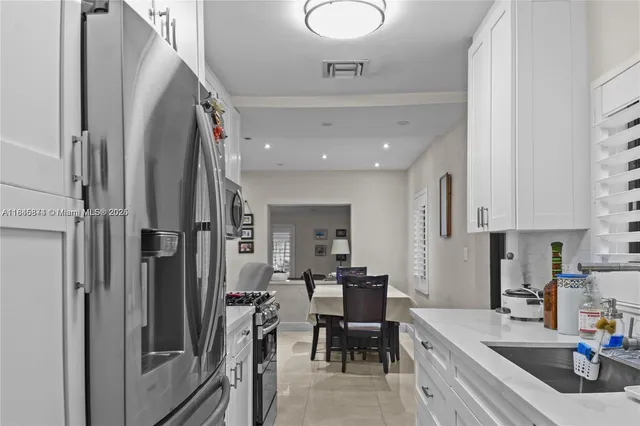 a kitchen with stainless steel appliances granite countertop a refrigerator a sink a stove and a dining table with wooden floor