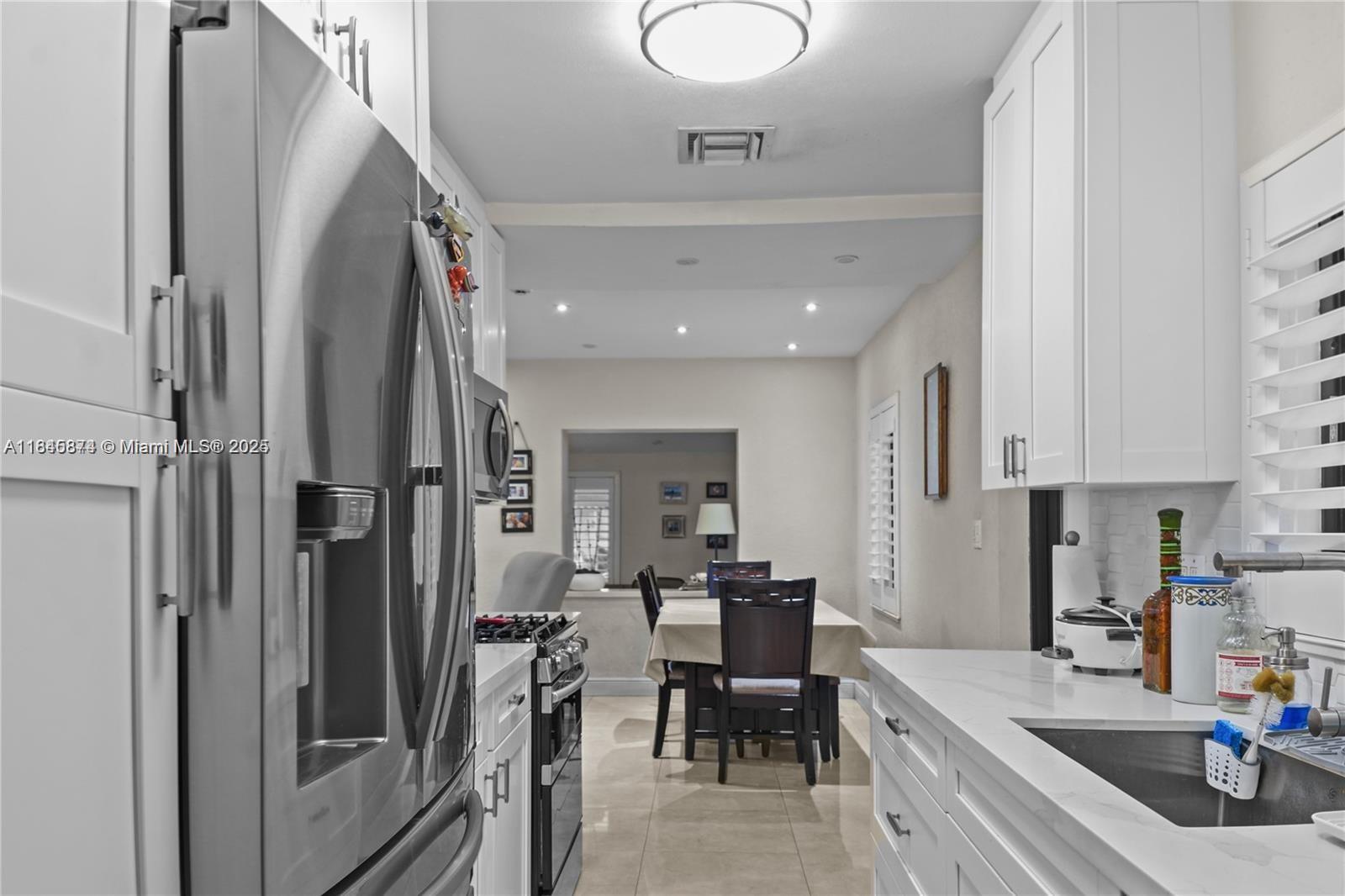 117 West 34th Street Hialeah, FL 33012 - Photo 11 of 27 a kitchen with stainless steel appliances granite countertop a refrigerator a sink a stove and a dining table with wooden floor