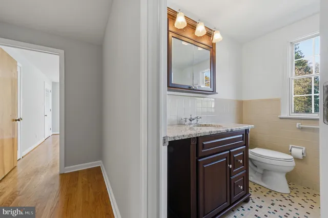 a bathroom with a granite countertop toilet a sink and a mirror