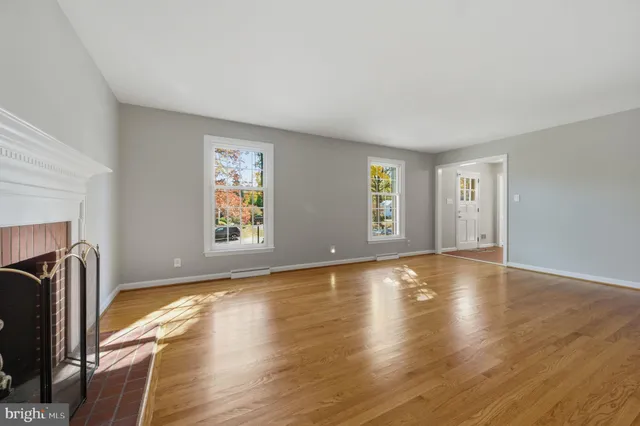 a view of an empty room with window and wooden floor