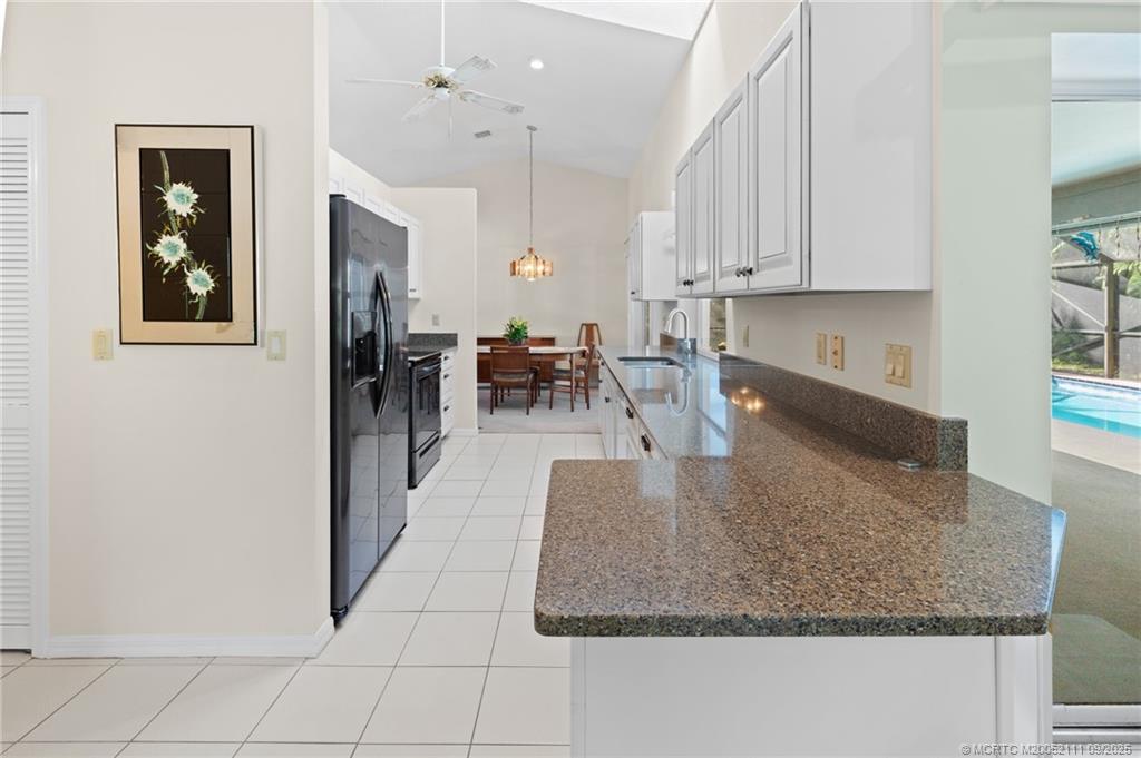 3418 Southeast Jamaica Way Stuart, FL 34997 - Photo 14 of 35 a kitchen with granite countertop a coffee maker a sink a window and white cabinets