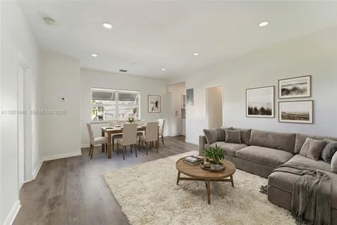 a living room with furniture and a dining table with rug