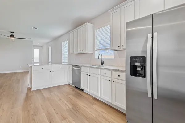 a kitchen with white cabinets and refrigerator