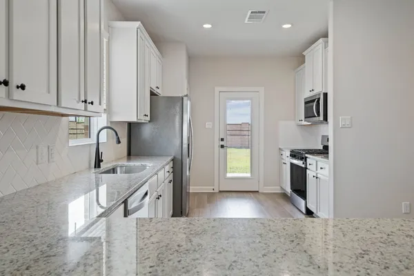 a kitchen with stainless steel appliances granite countertop a refrigerator a stove and a sink