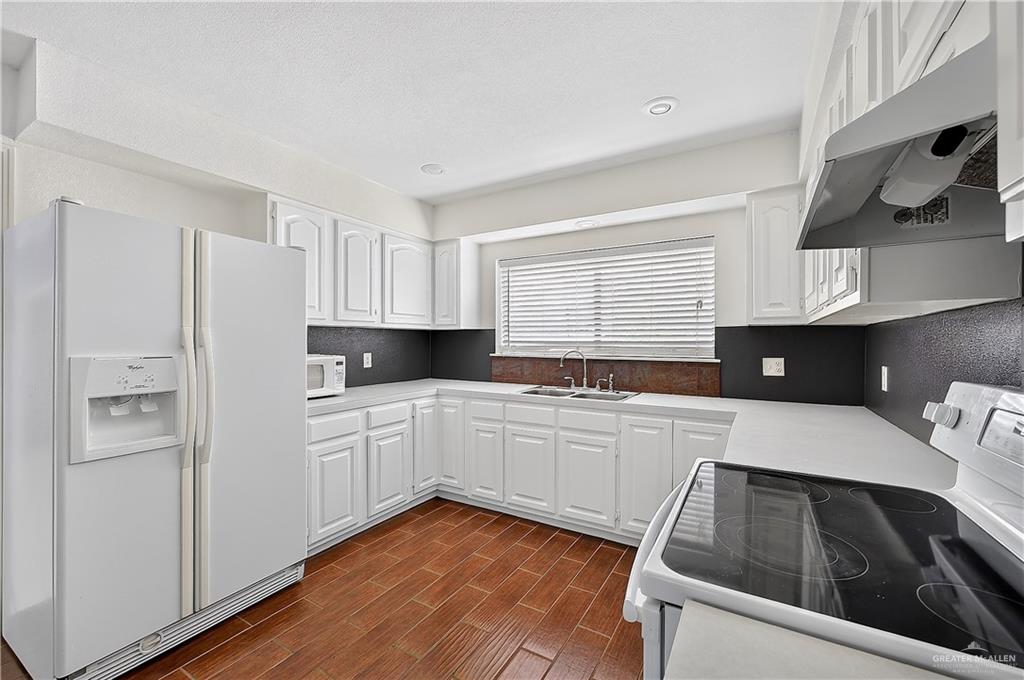 216 West Enfield Road Edinburg, TX 78539 - Photo 10 of 20 Kitchen featuring white cabinetry, white countertops, a stainless steel sink, wood-finish flooring, and recessed lighting