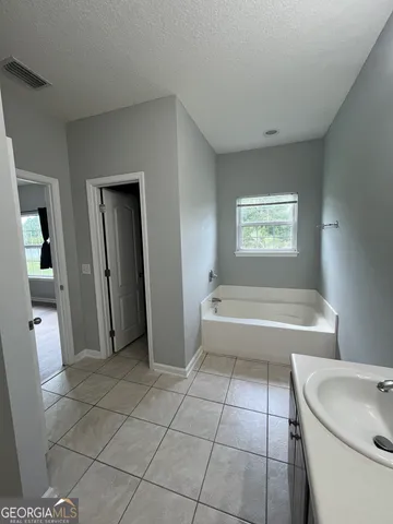 a bathroom with a tub a toilet a sink and a mirror