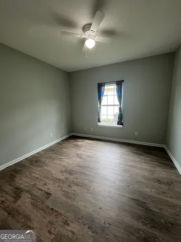 an empty room with windows and ceiling fan view