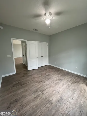 a view of empty room with wooden floor and ceiling fan