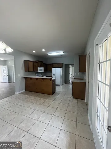 a living room with stainless steel appliances kitchen island granite countertop a refrigerator and a stove top oven