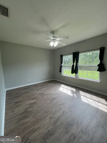 an empty room with large windows and a ceiling fan