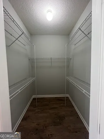 a empty room with walk in closet and wooden floor