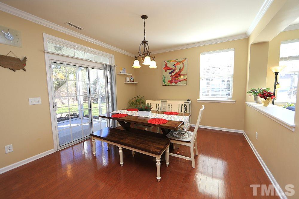 800 Roni Court Cary, NC 27519 - Photo 6 of 25 a dining room with wooden floor a chandelier a wooden table and chairs