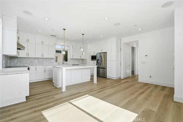 a large white kitchen with kitchen island a sink a center island stainless steel appliances and a cabinets